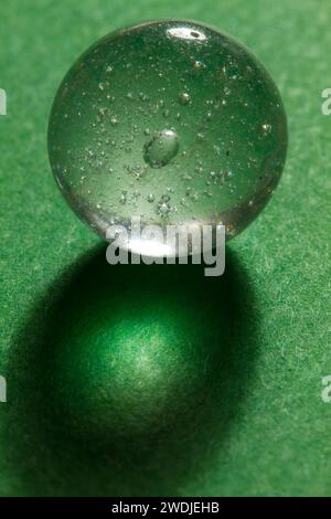 Un marbre de verre clair avec des bulles sur un fond vert. Banque D'Images