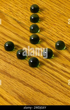 Un groupe de billes formant une flèche sur un plateau de jeu en bois. Banque D'Images