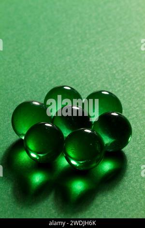 Billes de verre transparentes vertes sur fond vert. Banque D'Images