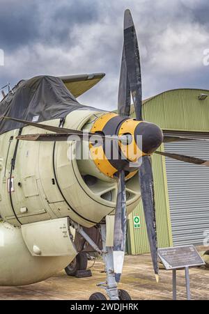 Un avion d'alerte précoce avec deux propulseurs exposé dans un musée de l'air. Le cockpit est couvert et il y a un hangar en arrière-plan. Un ciel avec Banque D'Images