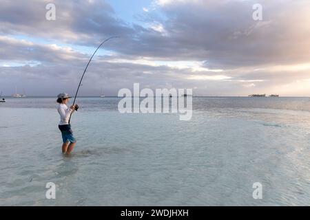 Touriste enfant en vacances, pêchant dans une eau peu profonde dans un lagon isolé d'une île tropicale de l'archipel de San Blas au coucher du soleil, Panama Banque D'Images