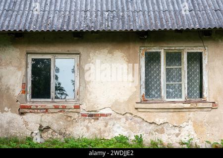 Mur de briques d'une vieille maison de campagne avec deux fenêtres en bois Banque D'Images