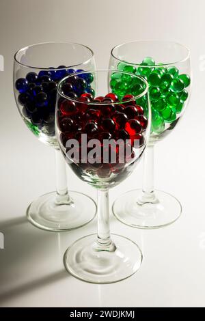 Billes rouges, bleues et vertes dans des verres à vin. Banque D'Images