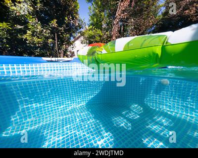 Spit vue sous-marine d'un matelas d'air dans une piscine privée entourée de végétation Banque D'Images