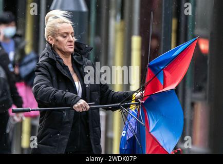 Une femme avec un parapluie cassé dans des conditions venteuses à Leeds. Le Royaume-Uni est couvert par des avertissements de vent « inhabituels » de danger pour la vie à l'approche de la tempête Isha, et les gens sont avertis de ne pas voyager en présence de rafales de 90 km/h. Date de la photo : dimanche 21 janvier 2024. Banque D'Images