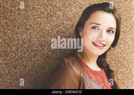 Gros plan portrait de belle jeune femme de 25-30 ans avec maquillage professionnel, portant une veste en cuir marron Banque D'Images