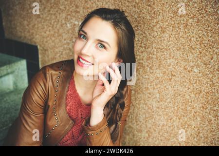 Gros plan portrait de belle jeune femme de 25-30 ans avec maquillage professionnel, portant une veste en cuir marron Banque D'Images