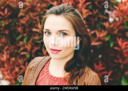 Gros plan portrait de belle jeune femme de 25-30 ans avec maquillage professionnel, portant une veste en cuir marron Banque D'Images