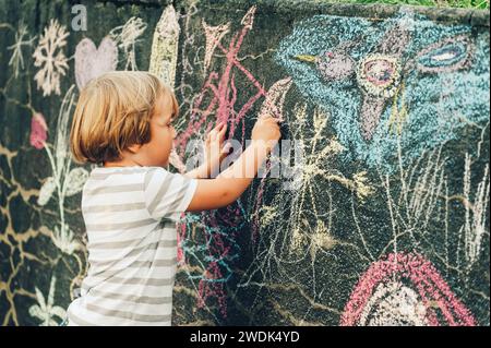 Adorable petit garçon dessin avec une craie à l'extérieur. Activités extérieures pour les enfants Banque D'Images