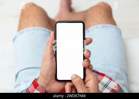 Vue de dessus de l'écran blanc du téléphone intelligent dans les mains masculines. Banque D'Images