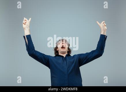 Triomphe personnifié comme un homme aux cheveux bouclés lève les poings dans l'air, hurlant de ferveur joyeuse Banque D'Images