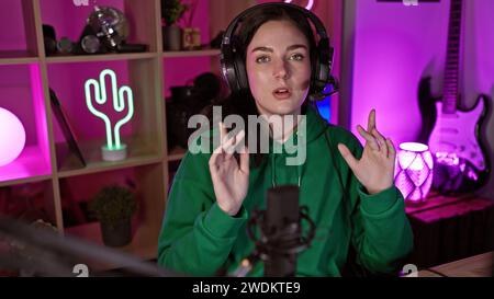 Une jeune femme dans un casque diffuse depuis une salle de jeux animée éclairée par des néons la nuit. Banque D'Images