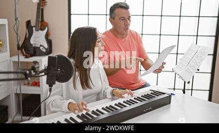 Des musiciens souriants, hommes et femmes, se sont imprégnés de leur leçon de studio de musique, harmonisant les mélodies sur piano acoustique tout en chantant ensemble Banque D'Images