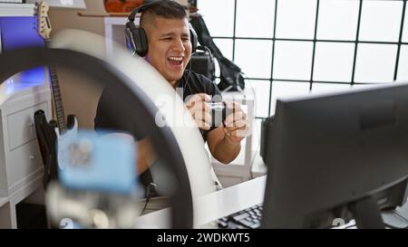 Smiling latin Streamer, appel vidéo en direct d'un jeune homme au cours d'une session de jeu passionnante dans son studio de musique Banque D'Images