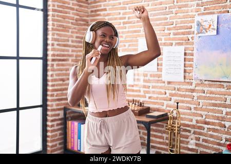 Femme afro-américaine écoutant de la musique chantant à la maison Banque D'Images