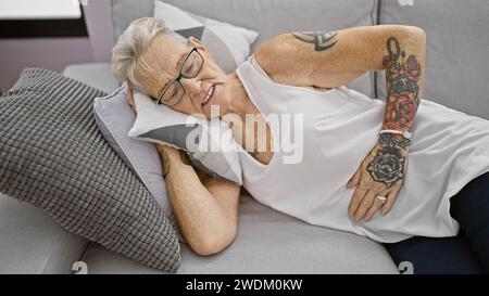 Malheureuse femme âgée aux cheveux gris souffrant de graves maux d'estomac tout en se reposant sur un canapé à la maison Banque D'Images