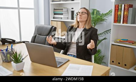 Bijou d'affaires blonde! jeune femme travailleur frappe poses de yoga au bureau, calme au milieu du chaos de travail en ligne Banque D'Images