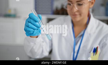 Brillante jeune femme rousse scientifique engrosée dans la recherche médicale, mesurant méticuleusement le liquide dans un tube à essai, gants de sécurité sur, à la h occupé Banque D'Images
