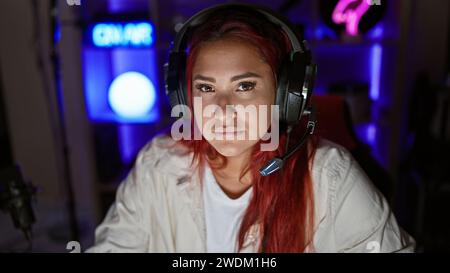 Streamer pour jeune femme rousse, plongé dans une séance de jeu intense, dans un jeu virtuel sérieux, casque allumé, encapsulé dans un éclairage tamisé Banque D'Images