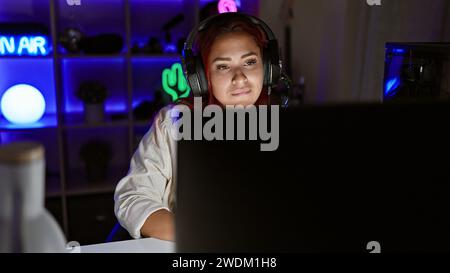 Streamer pour jeune femme rousse, plongé dans une séance de jeu intense, dans un jeu virtuel sérieux, casque allumé, encapsulé dans un éclairage tamisé Banque D'Images