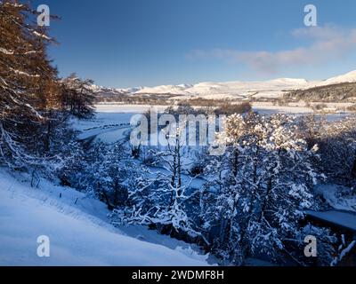 Glace flottant sur la rivière Spey près de Kingussie dans la neige d'hiver dans le parc national de Cairngorms, Écosse, Royaume-Uni, regardant vers les montagnes Monadliath. Banque D'Images