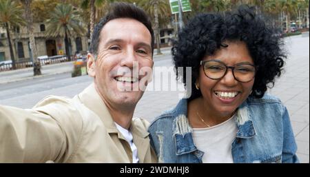 Perspective selfie d'un couple de touristes d'âge moyen diversifié prenant un selfie dans une ville. Couple hétérosexuel en vacances Banque D'Images