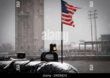 Un drapeau américain sur la poupe de l'USS Cobia (SS245), pendant une tempête de neige, et une partie du Wisconsin Maritime Museum à Manitowoc, Wisconsin. Banque D'Images