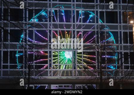 Leipzig, Allemagne. 21 janvier 2024. Une grande roue illuminée se reflète dans la façade vitrée de l'ancien bureau de poste principal sur Augustusplatz. Le trajet fait partie du « Leipzig Ice Dream ». Selon les organisateurs, la plus grande ronde, patinoire mobile en Allemagne attire les visiteurs à patiner jusqu'au 03.03.2024. Crédit : Sebastian Willnow/dpa/Alamy Live News Banque D'Images