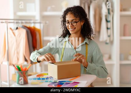 Boîte d'ouverture de femme souriante dans le studio de design Banque D'Images