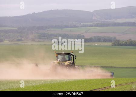 Nuages de poussière suivant un tracteur Claas avec des rouleaux Dalbo sur des terres agricoles dans l'Aberdeenshire au printemps Banque D'Images