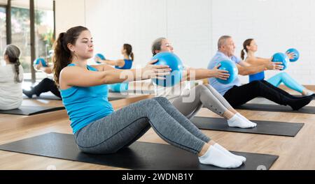 Jeune fille faisant des sit-ups avec balle de flexion dans le studio de Pilates Banque D'Images