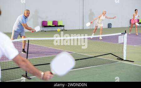 Homme sportif senior jouant au pickleball sur un terrain intérieur Banque D'Images