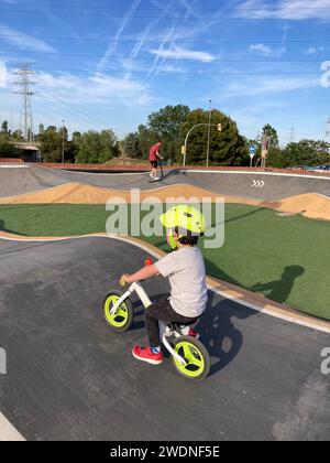 Vivifiant tour de pompe : enfant en casque sur un vélo blanc et vert fluorescent, la course à travers des virages passionnants Banque D'Images