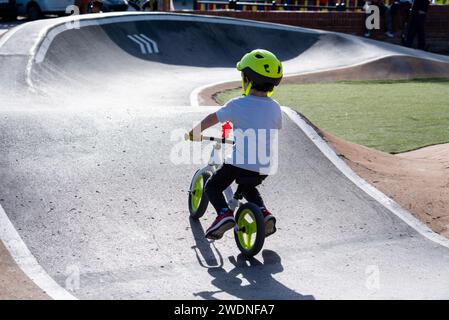 Vivifiant tour de pompe : enfant en casque sur un vélo blanc et vert fluorescent, la course à travers des virages passionnants Banque D'Images