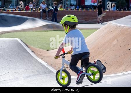 Vivifiant tour de pompe : enfant en casque sur un vélo blanc et vert fluorescent, la course à travers des virages passionnants Banque D'Images