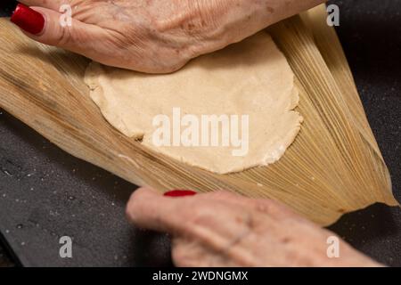 Procédé de fabrication de tamales de Chili ancho rouge maison assemblées sur des enveloppes de maïs et nouées Banque D'Images