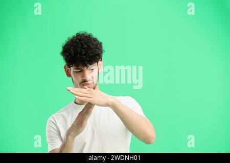Un homme, sur fond vert, en gros plan, montre un signe de pause Banque D'Images
