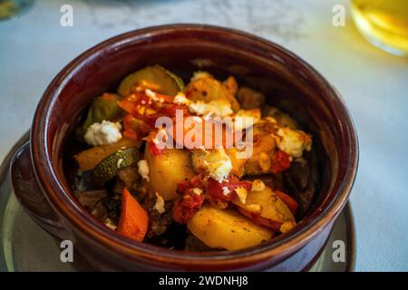 Légumes frais cuits tels que courgettes et pommes de terre avec fromage feta sur le dessus, cuisine grecque, briam grec traditionnel de style moderne avec légumes tranchés Banque D'Images