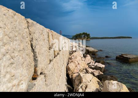 Quai rocheux en été ensoleillé à la plage méditerranéenne en Europe. Mur de pierres. Retraite de vacances tranquille. Évasion idyllique. Plage éloignée. Bord de mer calme. Banque D'Images