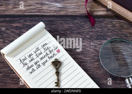 Citation manuscrite chrétienne pour chercher Dieu Jésus-Christ avec tout coeur, clé ancienne, loupe et livre Saint de la bible sur bois. Banque D'Images