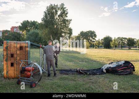 L'homme prépare un panier d'une montgolfière pour un vol tôt le matin à Klaipeda ville Meadown. Banque D'Images