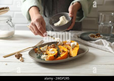 Femme mettant du fromage sur des tranches de citrouille cuites à table, gros plan Banque D'Images