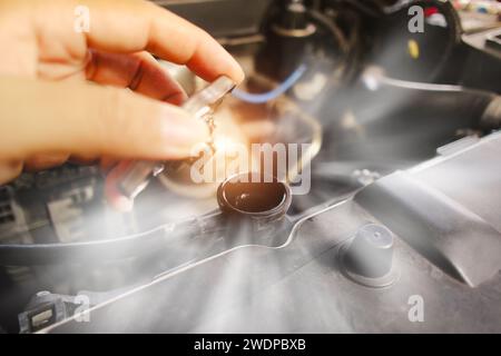 La main mécanique automatique ouvre le bouchon du radiateur avec de la vapeur s'échappant autour du compartiment moteur de la chaleur élevée , concept de service d'entretien de voiture. Banque D'Images