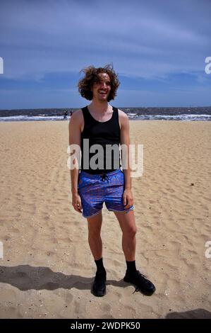 Jeune bel homme debout sur une plage de sable Banque D'Images