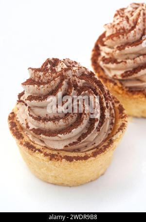 Deux mini tartelettes tiramisu isolées sur blanc saupoudrées de cacao. mise au point sélective. Espace de copie Banque D'Images