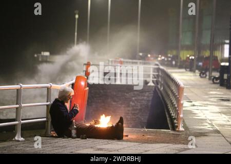 Aberystwyth pays de Galles UK météo 22 janvier 2024 Un homme sans abri sort de la tempête Isha alors que de grosses vagues s'écrasent sur la promenade, Credit : mike davies/Alamy Live News Banque D'Images