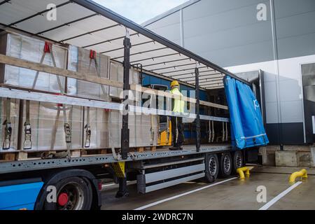 Récepteur d'entrepôt debout à l'intérieur du camion dans la zone de cargaison, remorque. Réceptionniste tenant la tablette, regardant les détails de la cargaison, vérifiant les articles livrés Banque D'Images