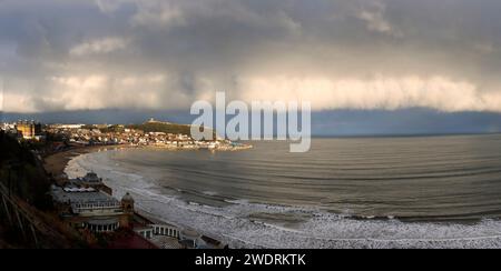 En fin d'après-midi, le soleil met en valeur la pointe du château à Scarborough alors que des nuages d'orage se profilent vers le nord. Le promontoire a fourni un abri contre les tempêtes Banque D'Images