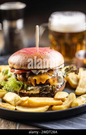 Hamburger de bœuf avec frites et bière pression sur une assiette de pub ou de restaurant. Banque D'Images