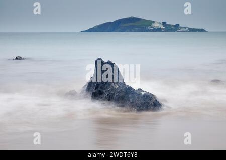 Une vue au crépuscule sur les rochers du rivage sur la plage de Bantham, avec une vue vers Burgh Island et son hôtel, sur la côte sud du Devon, en Angleterre Banque D'Images